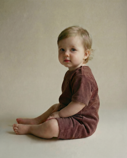 Tiny Terry relaxed terry romper worn by a baby sitting in a side-on view
