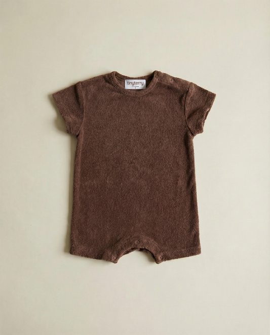 Tiny Terry relaxed terry romper in brown colour flat lay on neutral background on floor in soft natural light 